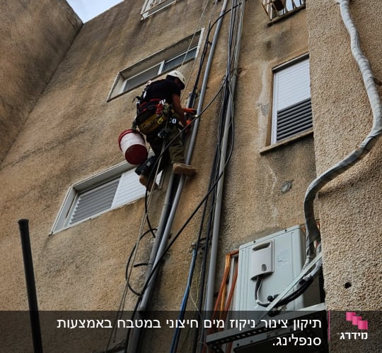 אדם מטפס על קיר עם ציוד טיפוס וחבלים